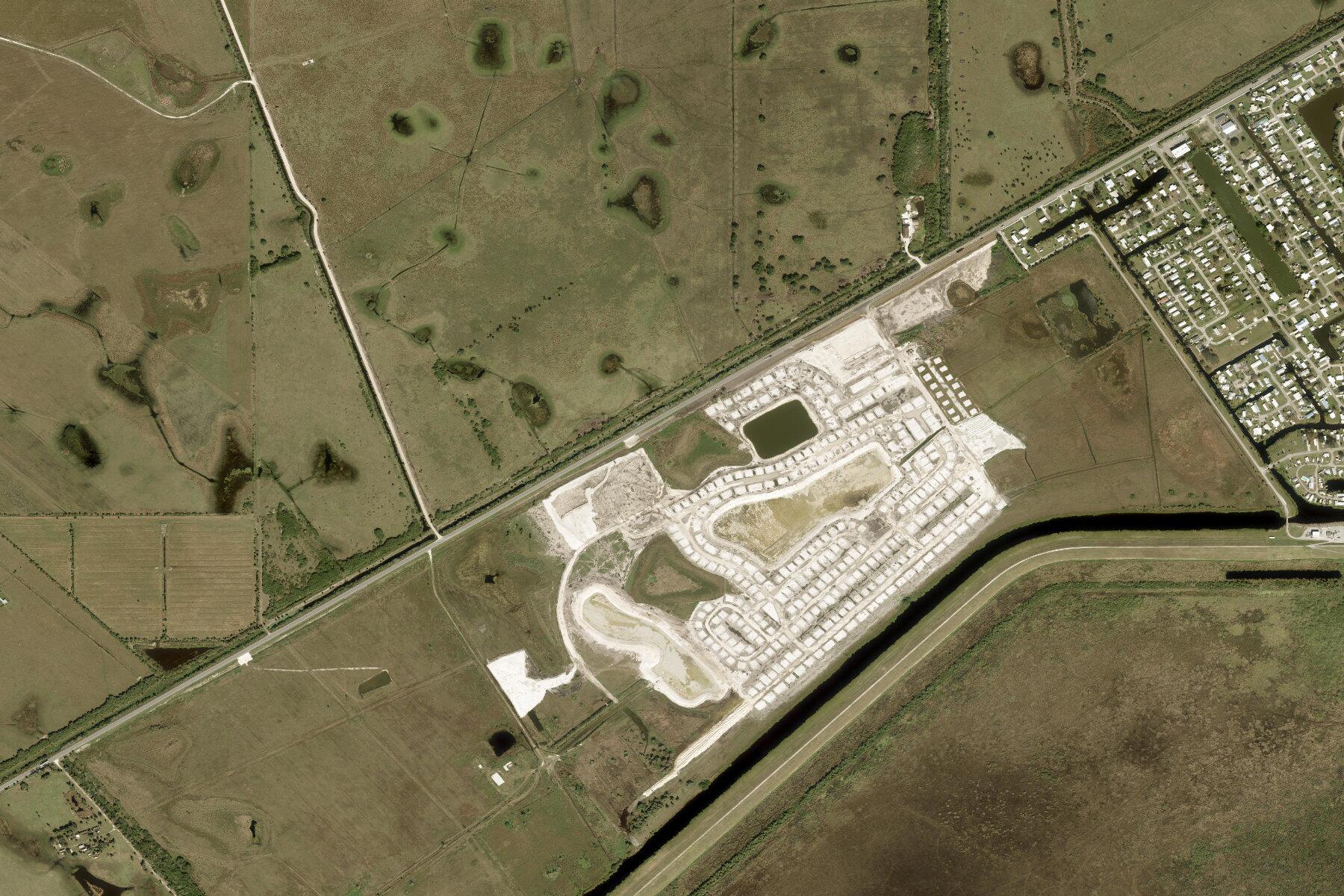 Satellite photograph of Lakefront Estates. The new street grid and lakes sit beside State Road 78, with open land to the west and a canal along the east side.
